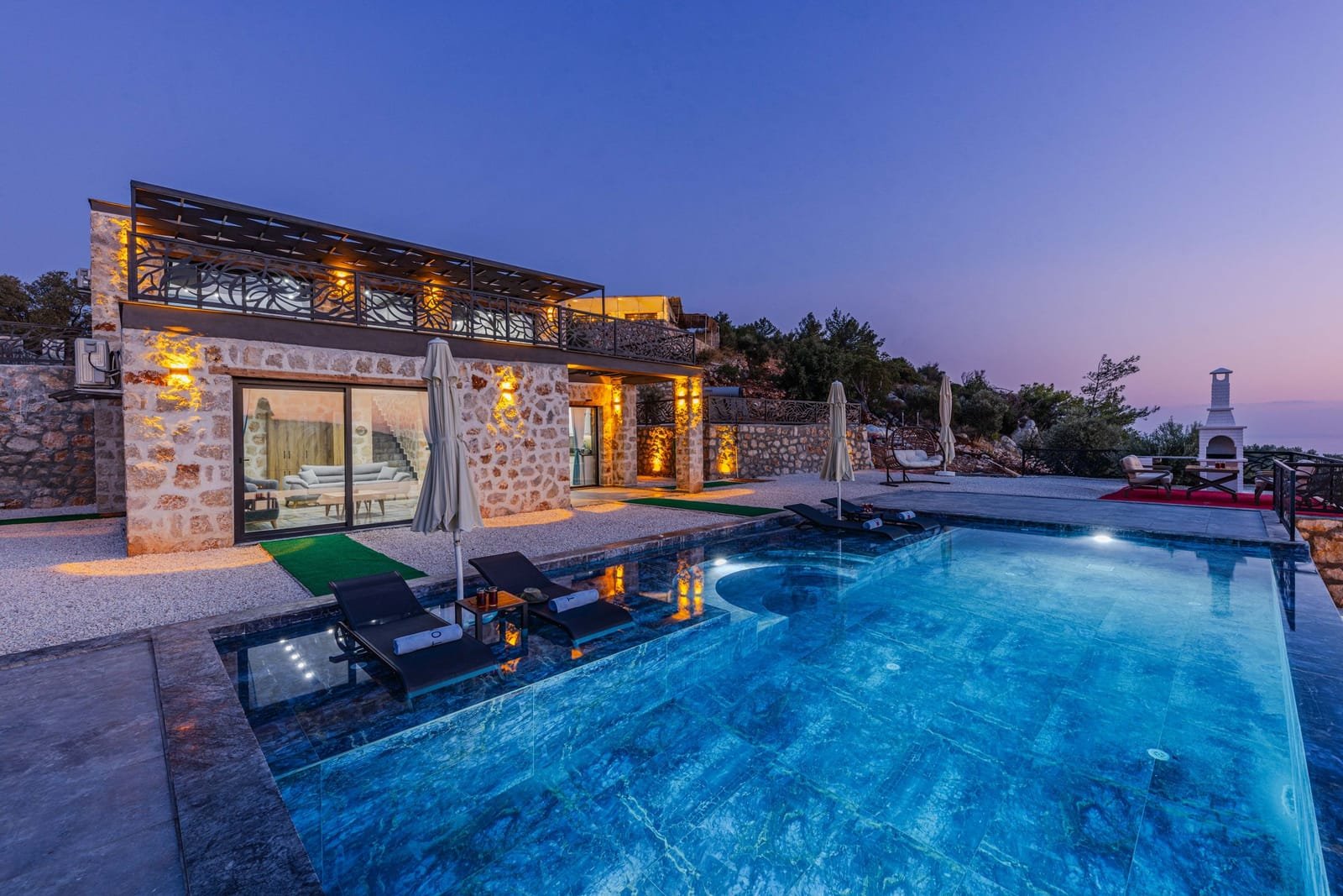 Luxury stone villa with infinity pool lit at dusk in Los Cabos
